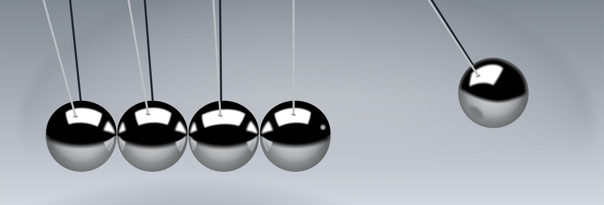 a close-up of a newton's cradle with one ball raised
