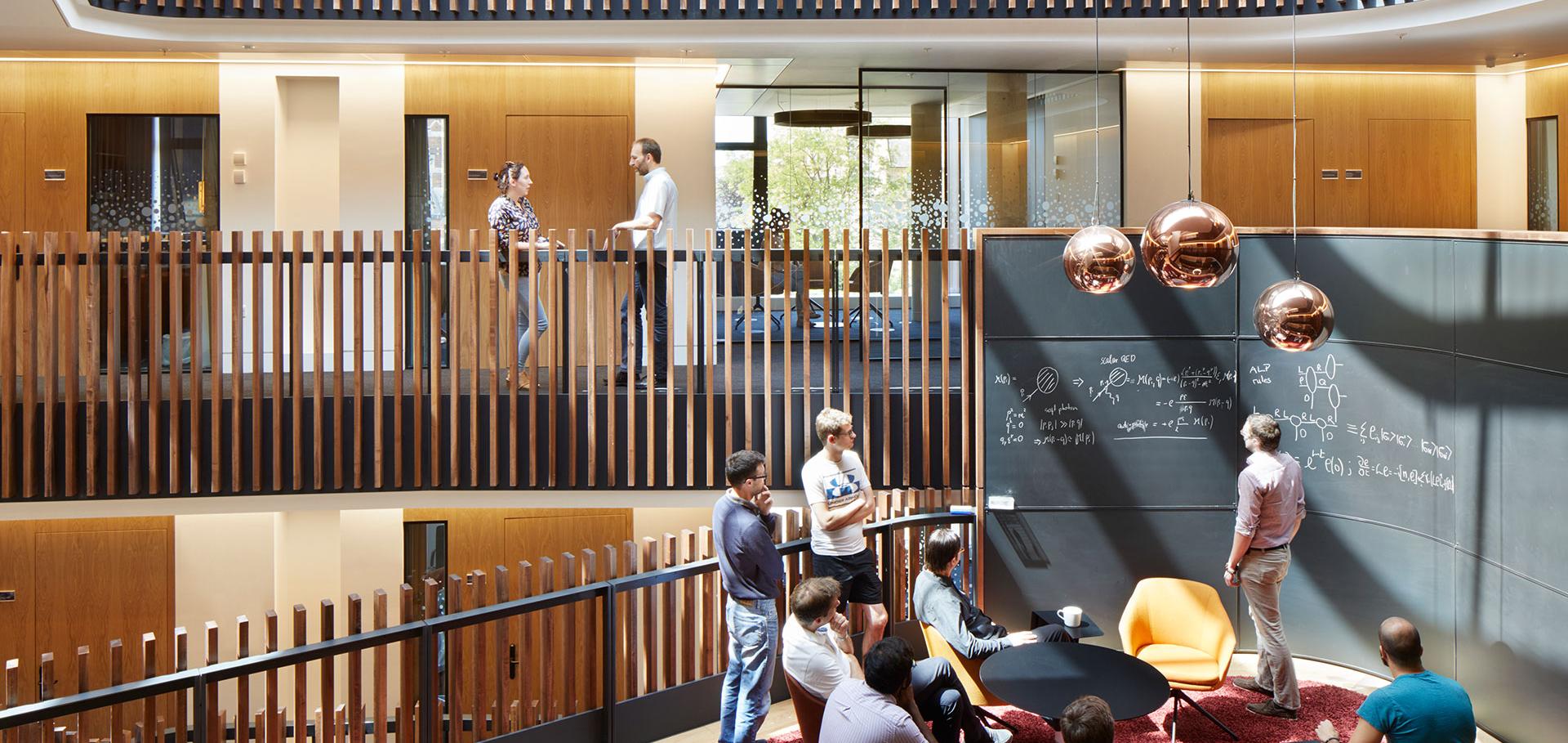 Theoretical physicists working at a blackboard collaboration pod in the Beecroft building.