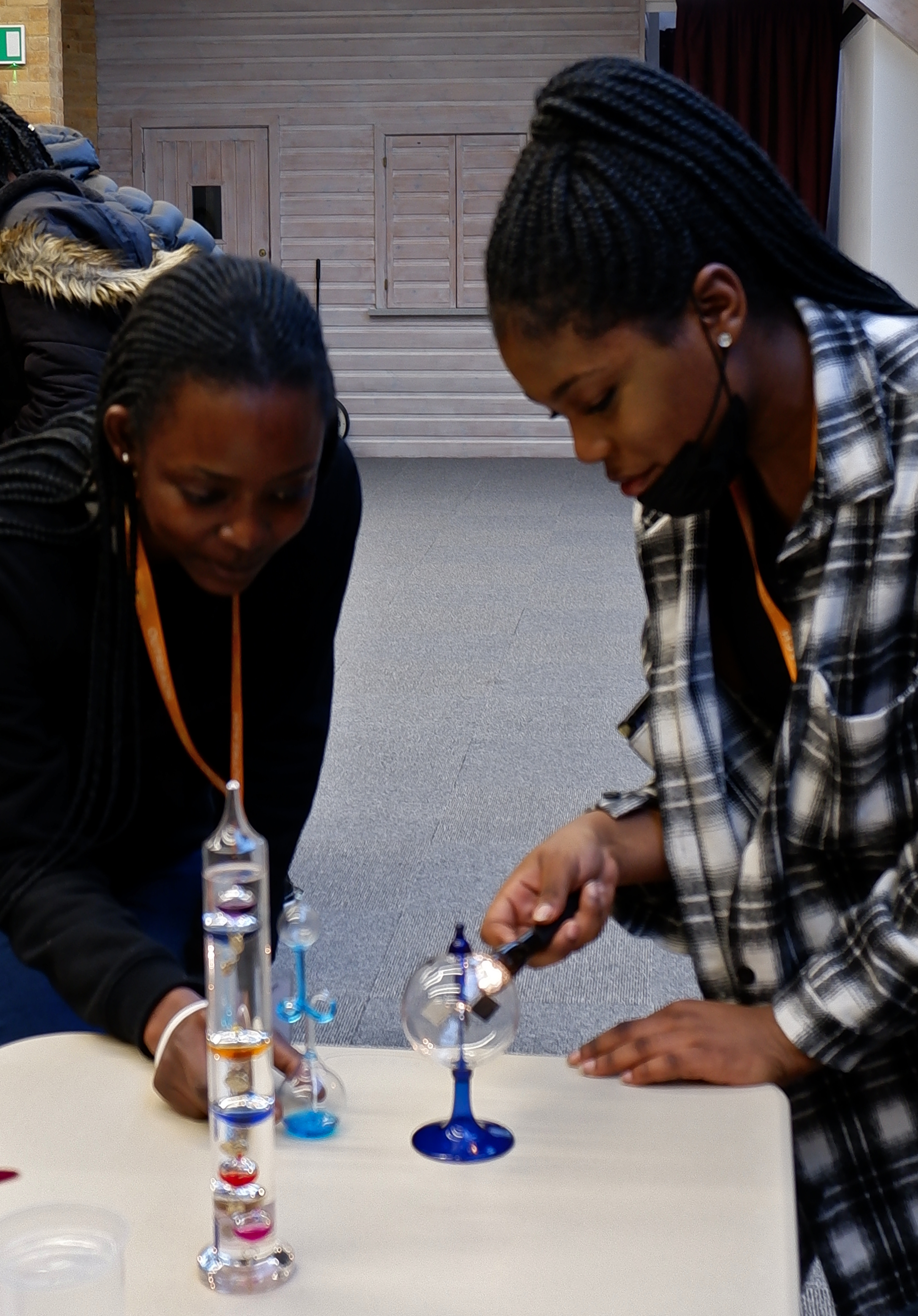 two young ladies are shining a torch on a crookes radiometer