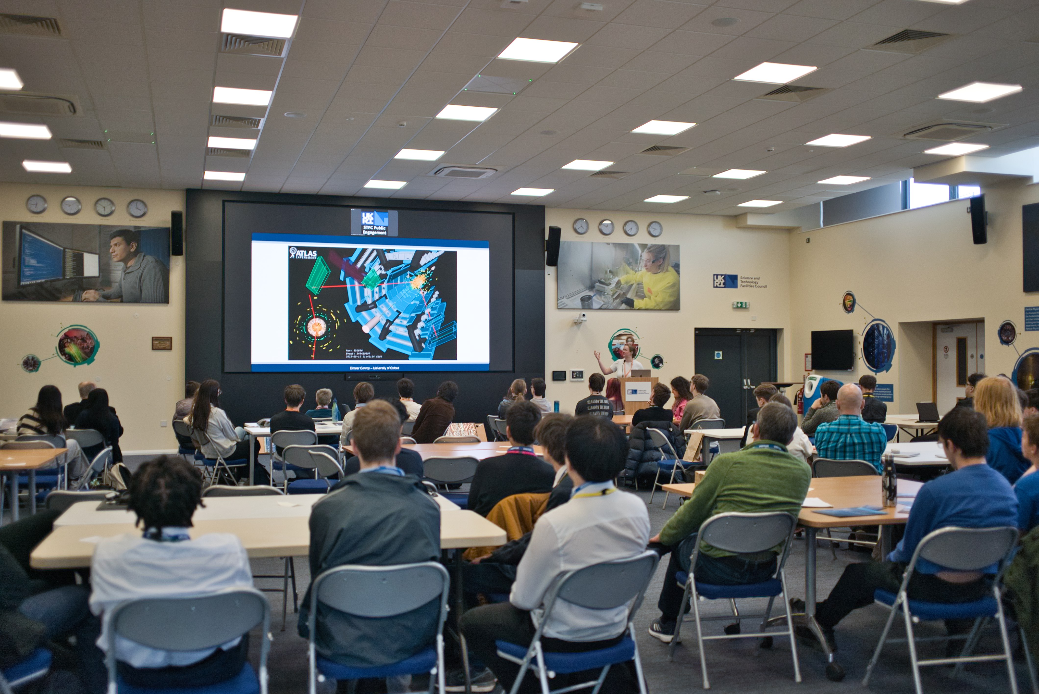 Image of students in a classroom with image from LHC on screen.