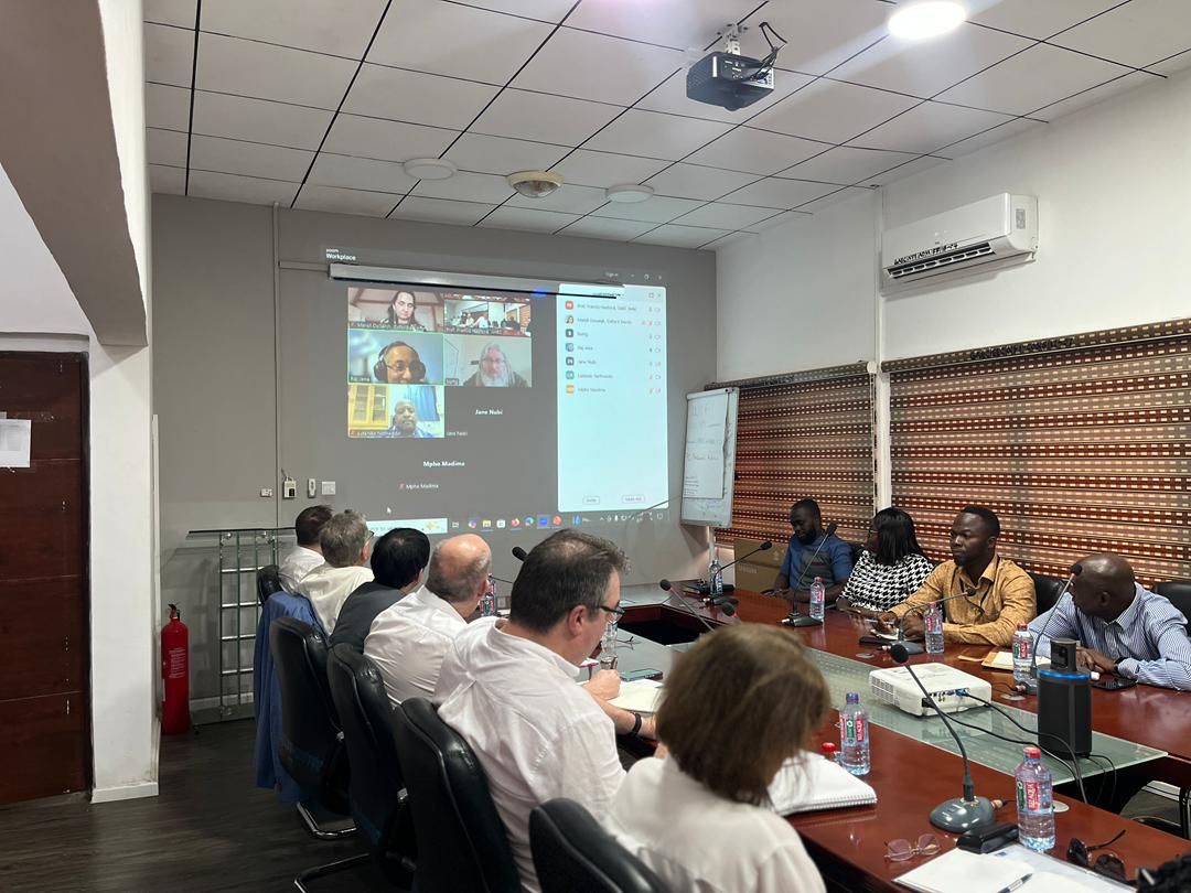 Image of meeting in room with Zoom call attendees projected on screen