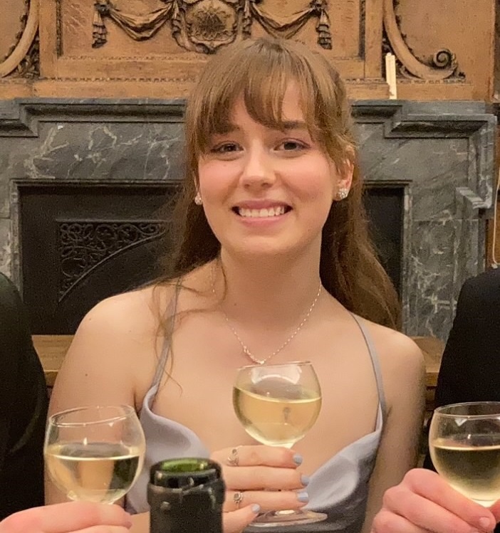 a photo of juliet in front of a fireplace with a glass of wine