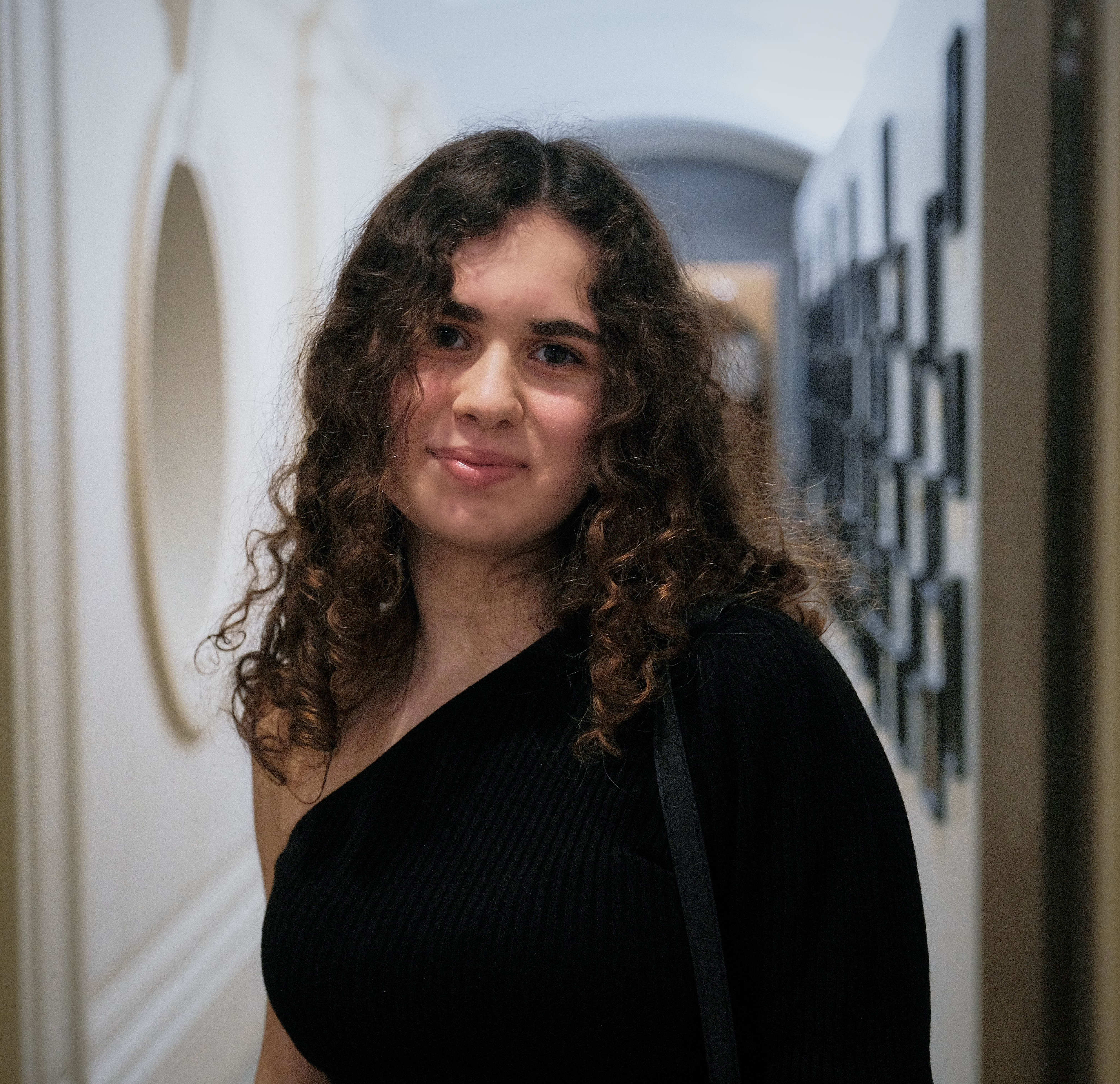 A photo of Yaprak in a black top in front of a corridor