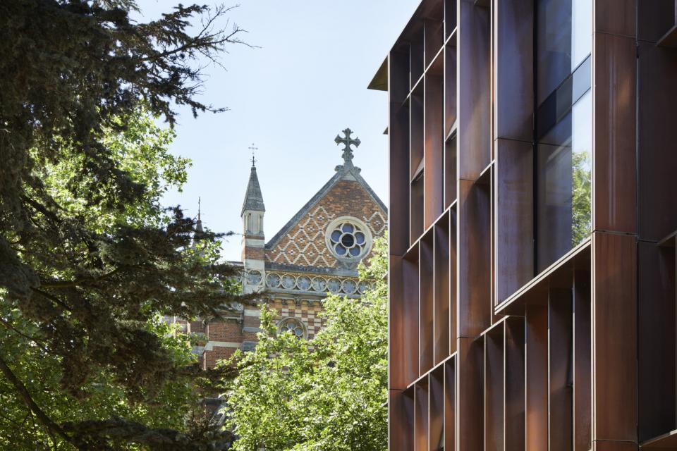 An image of a modern physics building with a tree and an older building  in the background.