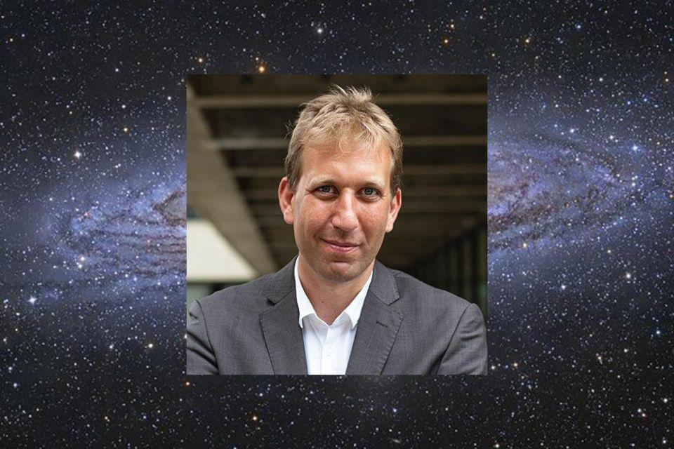 Image shows a galaxy with a super imposed portrait of Professor Chris Lintott