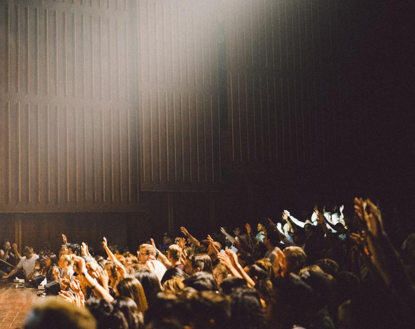 A photo of some students in a lecture theatre raising their hands