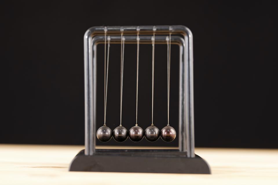 a newton's cradle toy against a black background