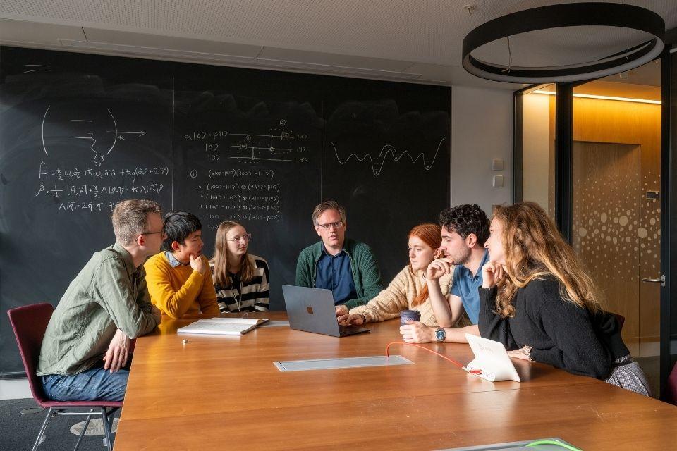 People sitting around a table with a blackboard in the background