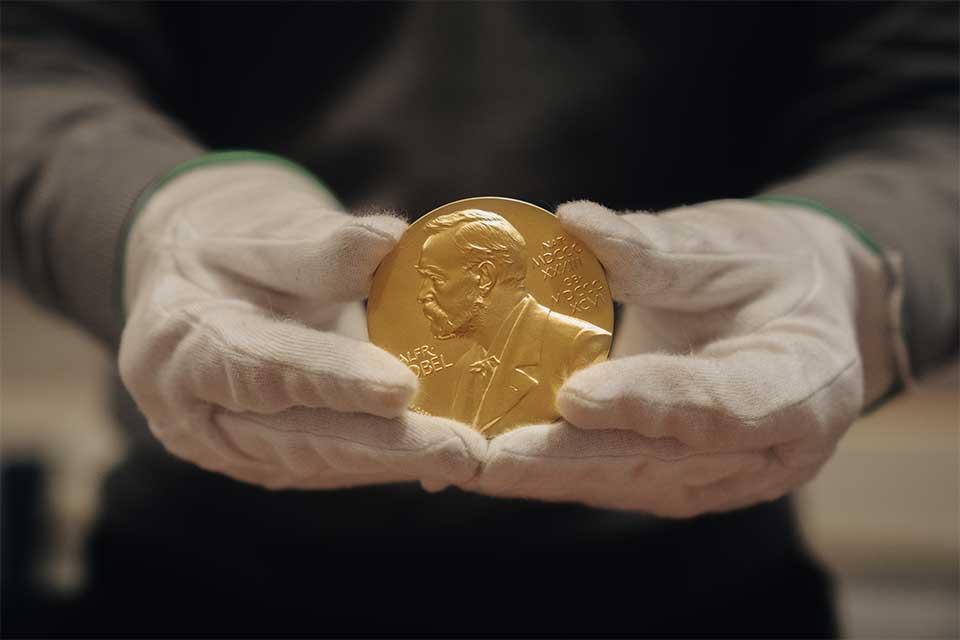 Nobel Prize medal held in gloved hands
