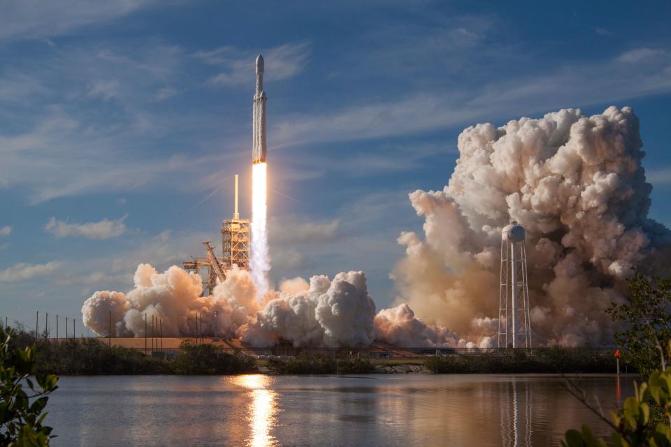 a photo of a space X rocket launch with big clouds of steam and a fiery rocket