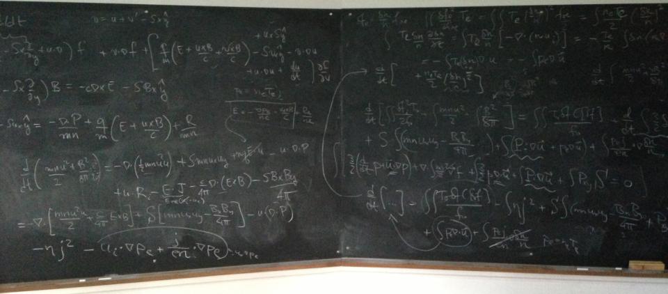 An image of a chalkboard covered in physics equations.