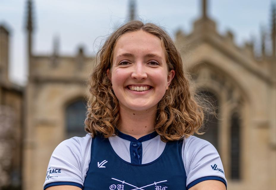 Image of Lilli Freischem smiling, wearing rowing uniform, with All Souls Library in the background