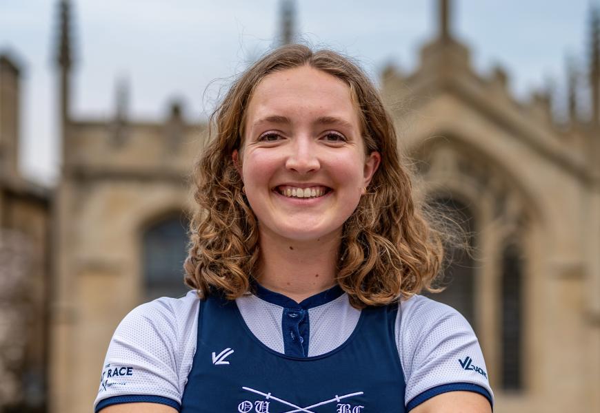 Image of Lilli Freischem smiling, wearing rowing uniform, with All Souls Library in the background