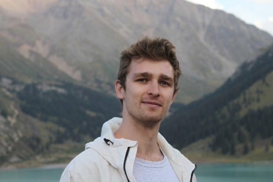 Dr Richard Nies in a white jacket with a mountain background. 