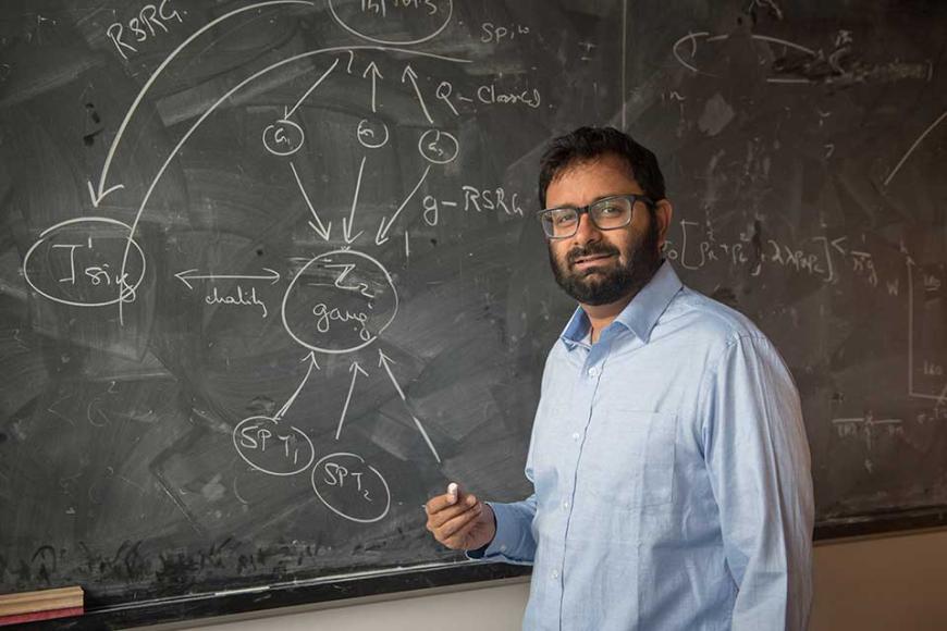 Professor Siddharth Parameswaran in front of a black chalk board