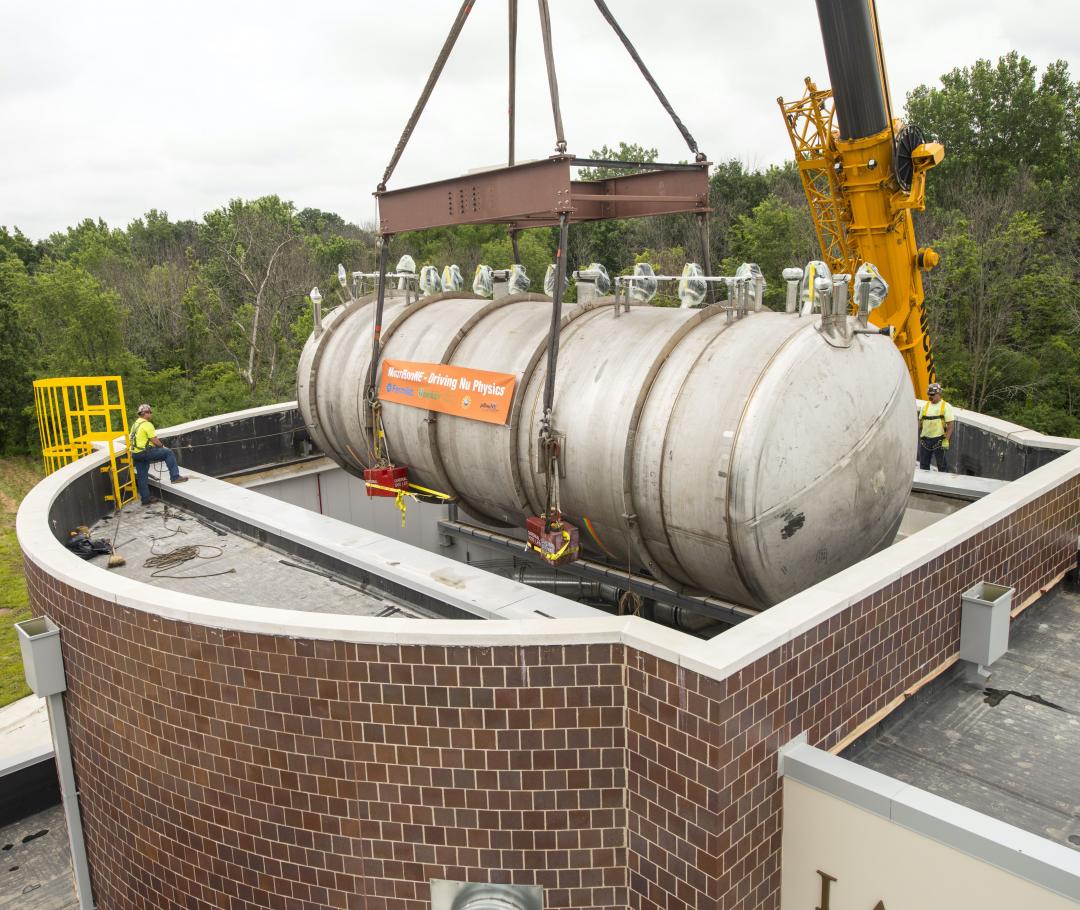 Photo of the MicroBooNE cryostat (containing the detector) being lowered by crane into the experimental hall through the roof