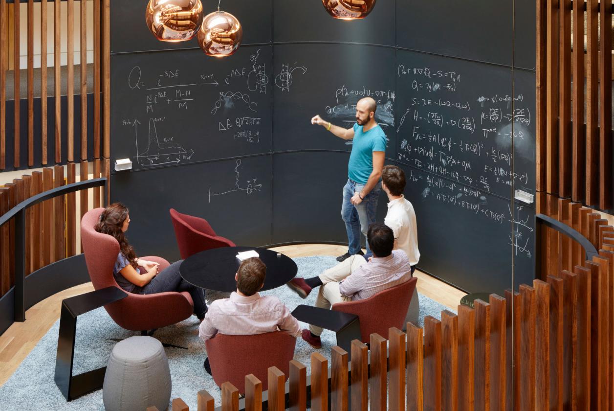 Postgraduate students talking around a blackboard