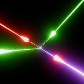 Illustration of photon-photon scattering in the laboratory. Two green petawatt lasers beams collide at the focus with a third red beam to polarise the quantum vacuum. This allows a fourth blue laser beam to be generated, with a unique direction and colour, which conserves momemtum and energy.