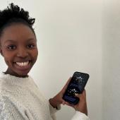 Female from South Africa holding a phone showing the STEP into the Cosmos webapp