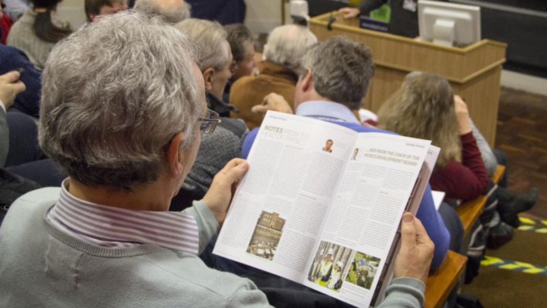 Alumnus reading a physics newsletter at an event