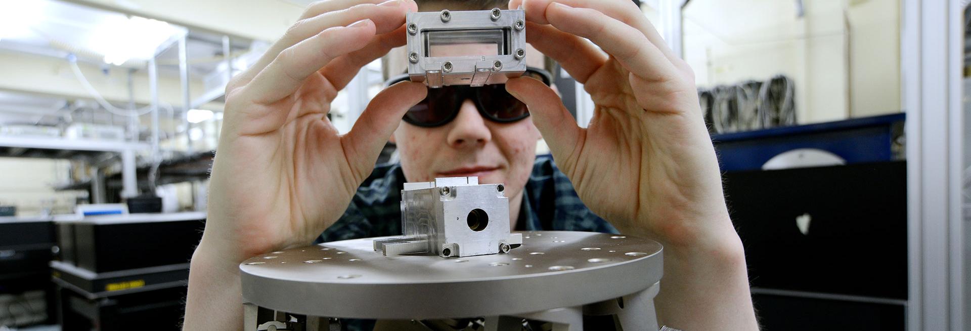 Male holding metal component with scientific instrument