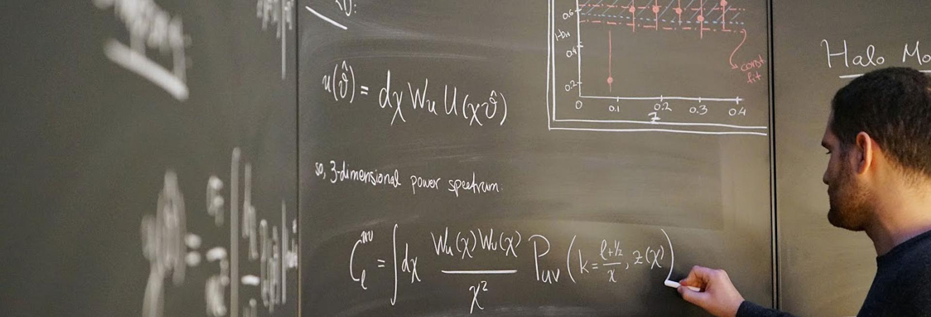 Male student at blackboard exploring an astrophysics problem