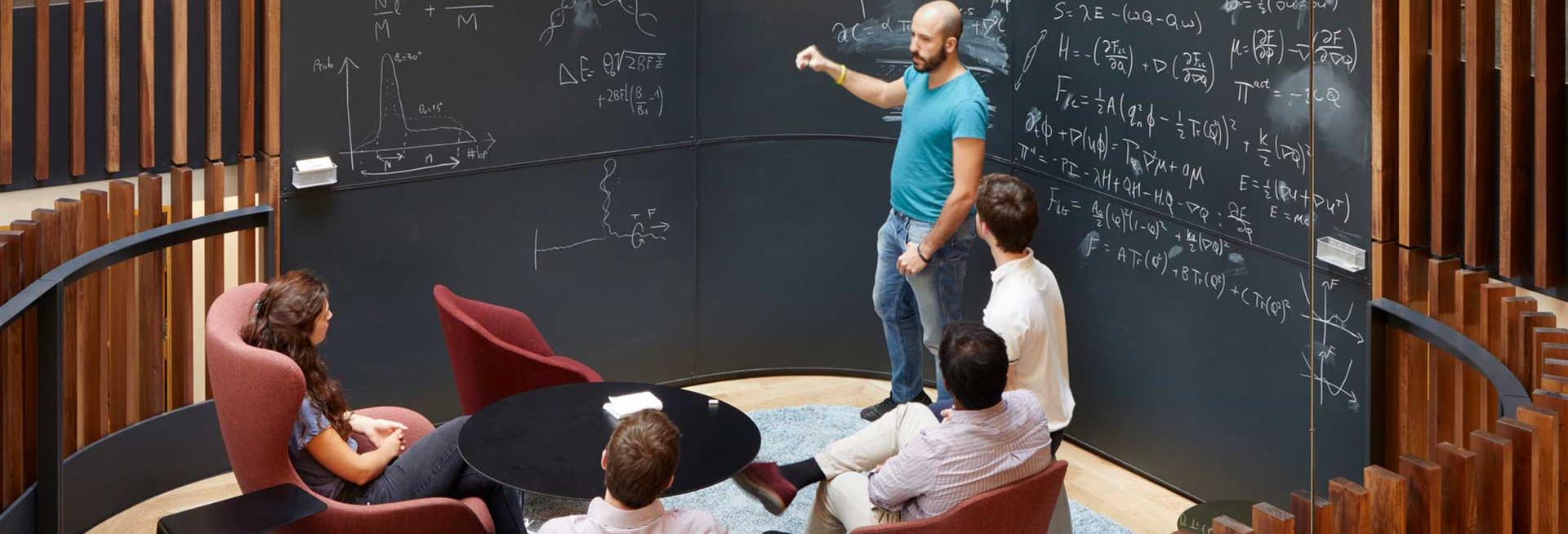 People around a blackboard discussing physics