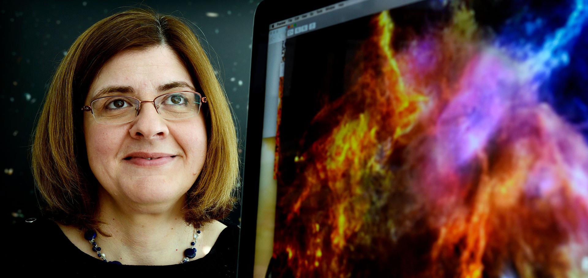 Head and shoulders of a woman next to a computer screen depicting physics