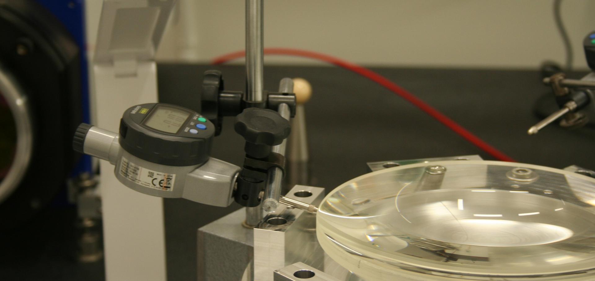 Lens being measured by a dial gauge in the lab, part of the assembly procedure