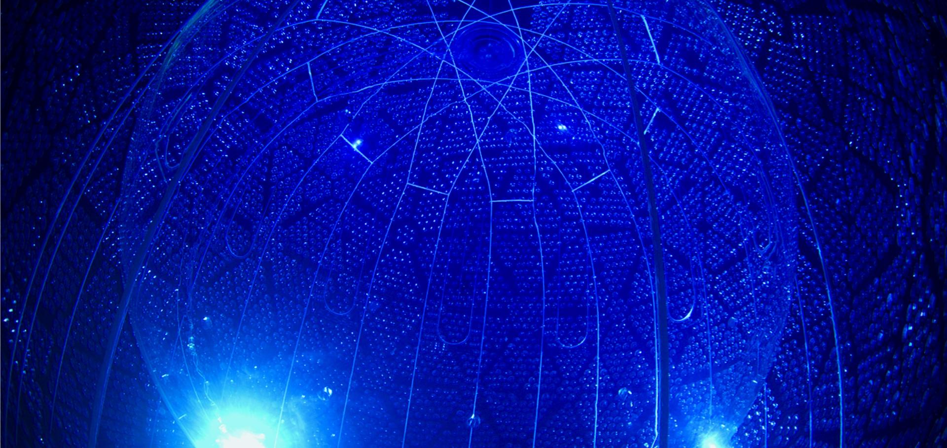 The SNO+ detector, featuring an inner spherical vessel with ropes to hold it in place. The PMTs around the edge are facing inwards towards the inner vessel. 