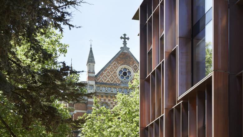 An image of a modern Oxford physics building with an older college building in the background