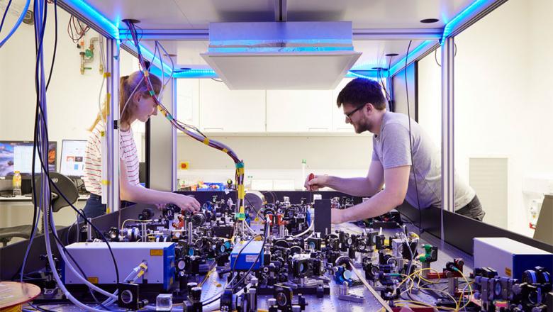 Two physicists (a female and male) working on a lab experiment
