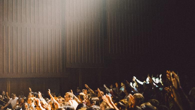 A photo of some students in a lecture theatre raising their hands