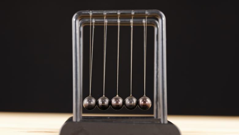 a newton's cradle toy against a black background