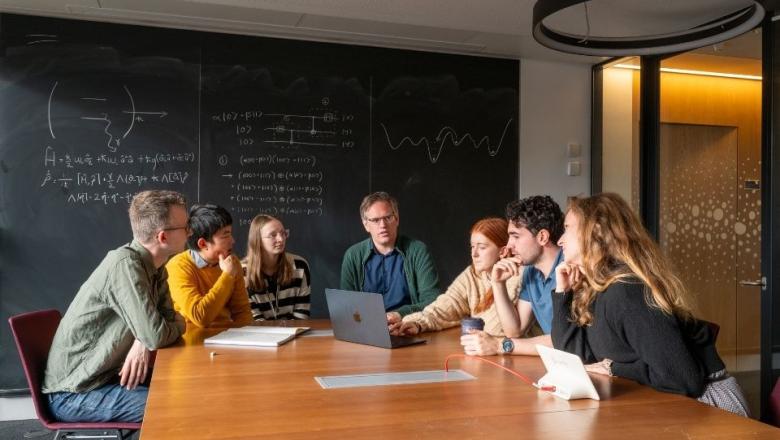 People sitting around a table with a blackboard in the background