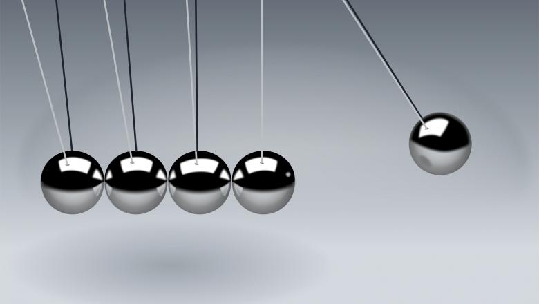 a newton's cradle with five balls, the right hand one is raised up and about to fall