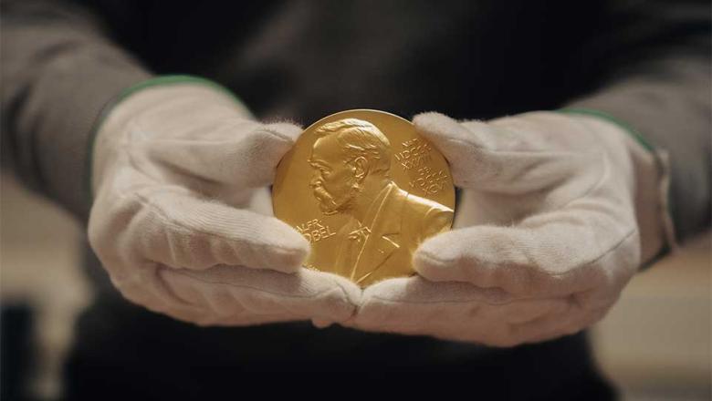 Nobel Prize medal held in gloved hands