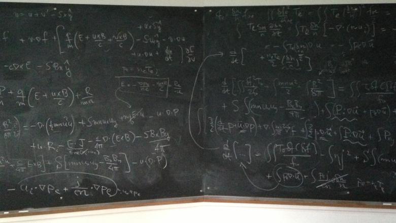 An image of a chalkboard covered in physics equations.